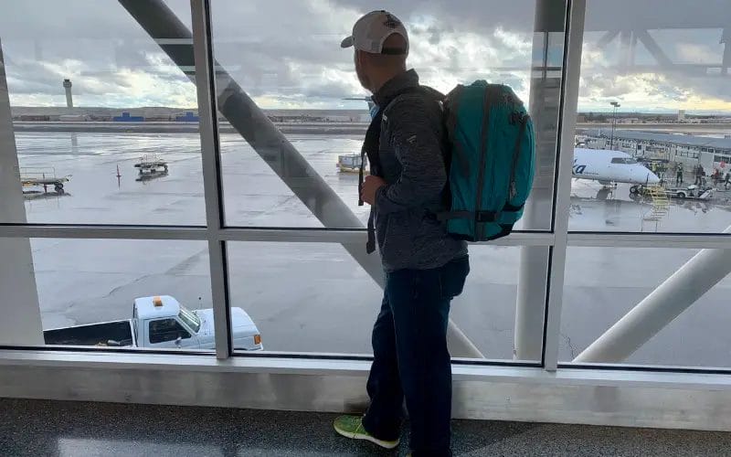 Man standing at airport with carry-on backpack\